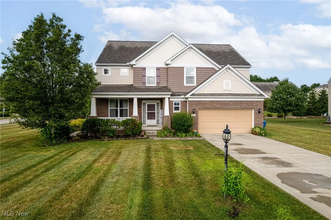 Craftsman inspired home featuring covered porch, brick siding, driveway, a front yard, and a garage