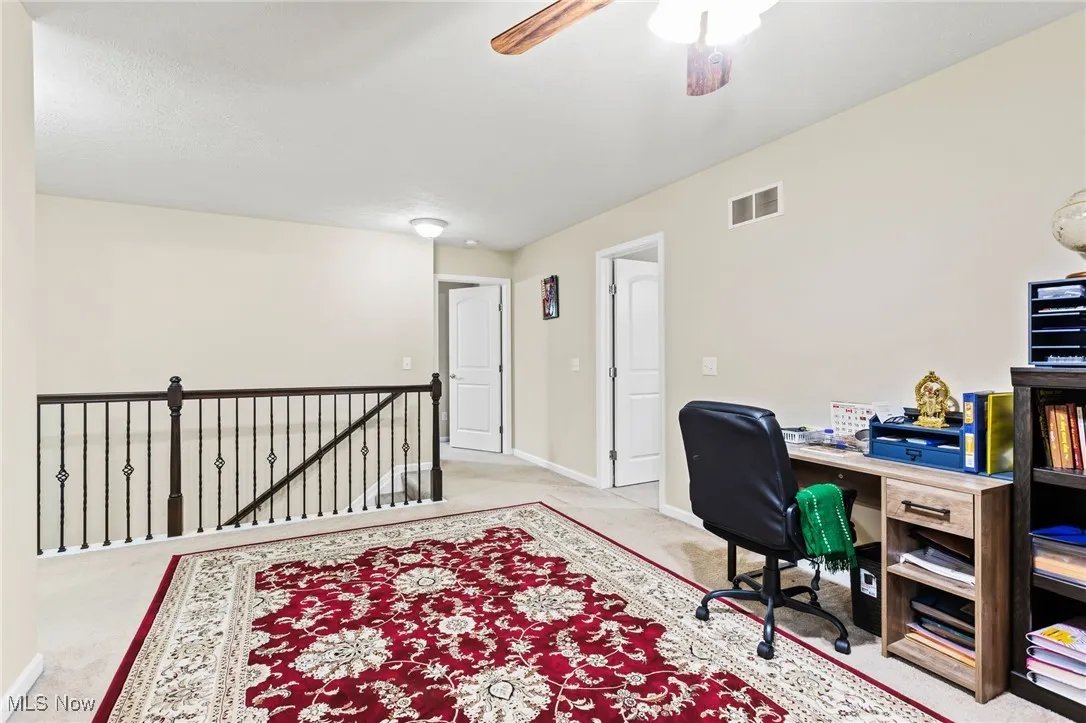 Carpeted office with baseboards and a ceiling fan