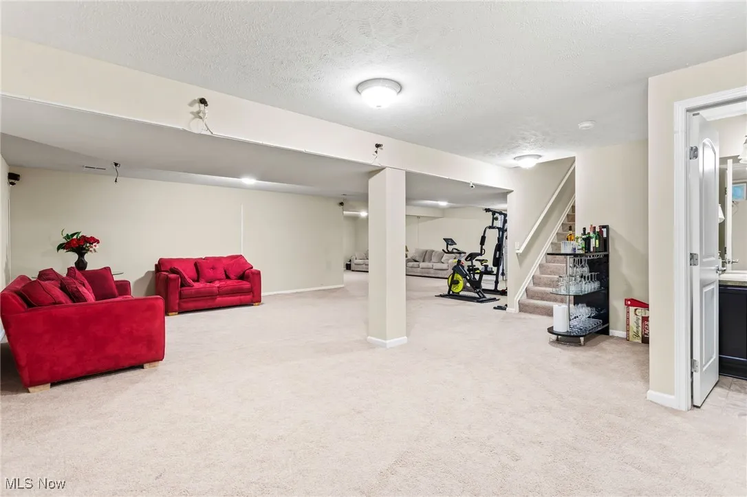 Finished below grade area featuring carpet floors, stairway, and a textured ceiling
