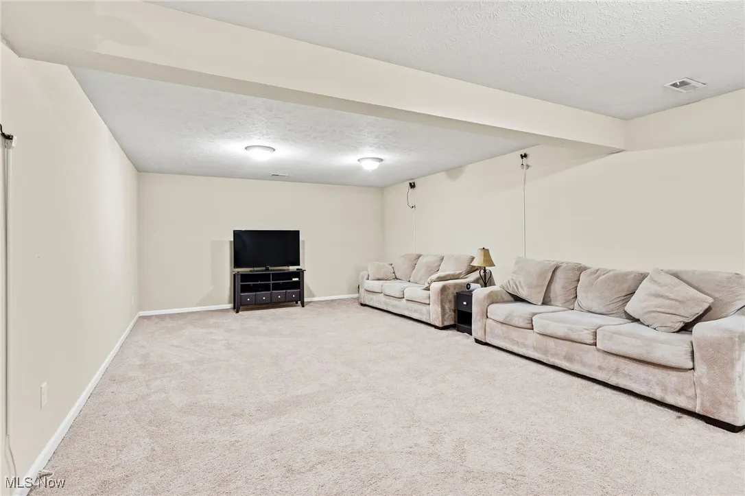 Carpeted living room featuring a textured ceiling and baseboards
