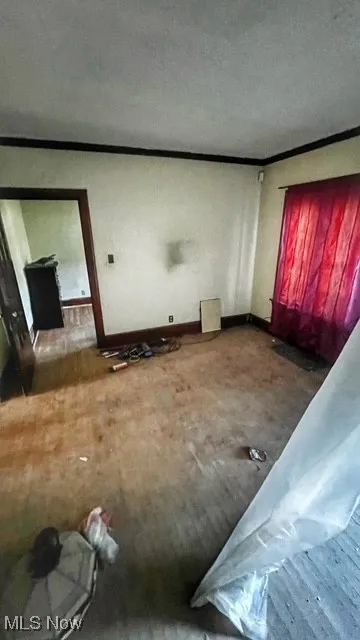 Unfurnished living room with baseboards and crown molding