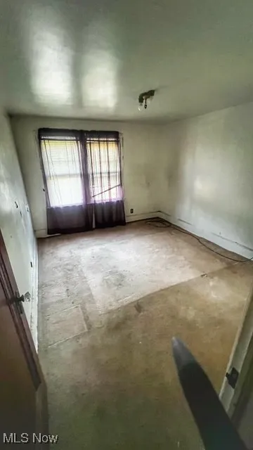 Unfurnished room with unfinished concrete flooring