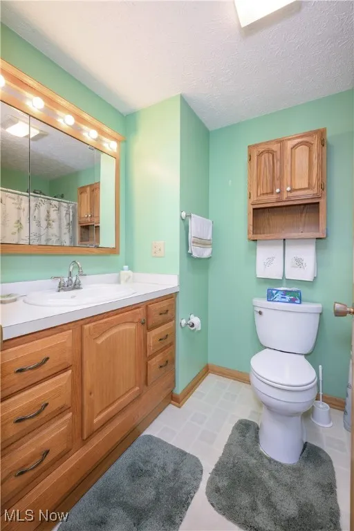 Full bathroom with vanity, a textured ceiling, and a shower with shower curtain