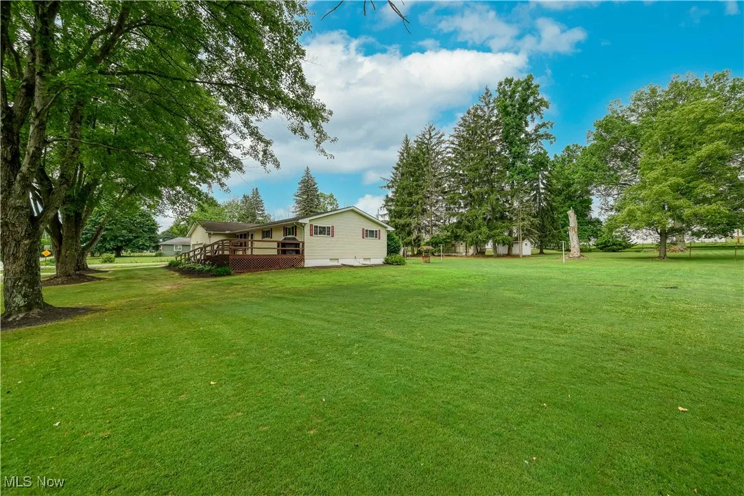 View of green lawn featuring a wooden deck
