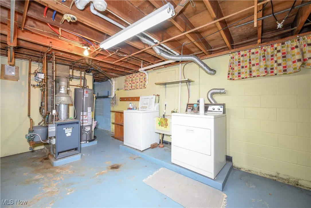 Unfinished basement with water heater and washing machine and clothes dryer