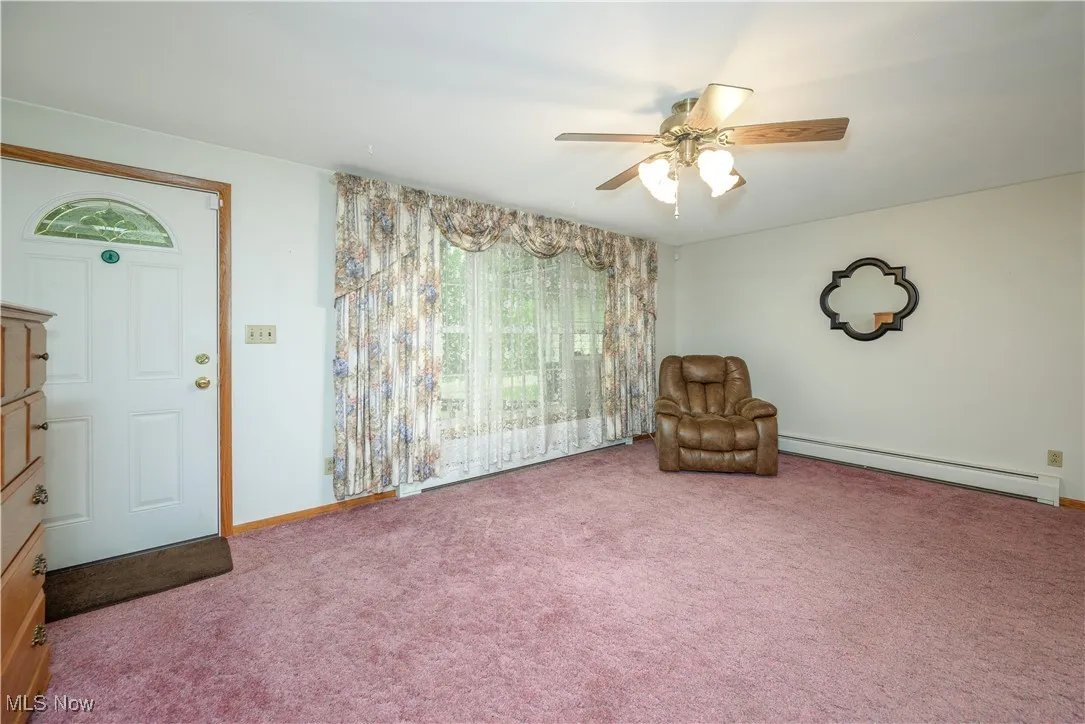 Unfurnished room featuring a baseboard radiator, carpet flooring, and ceiling fan