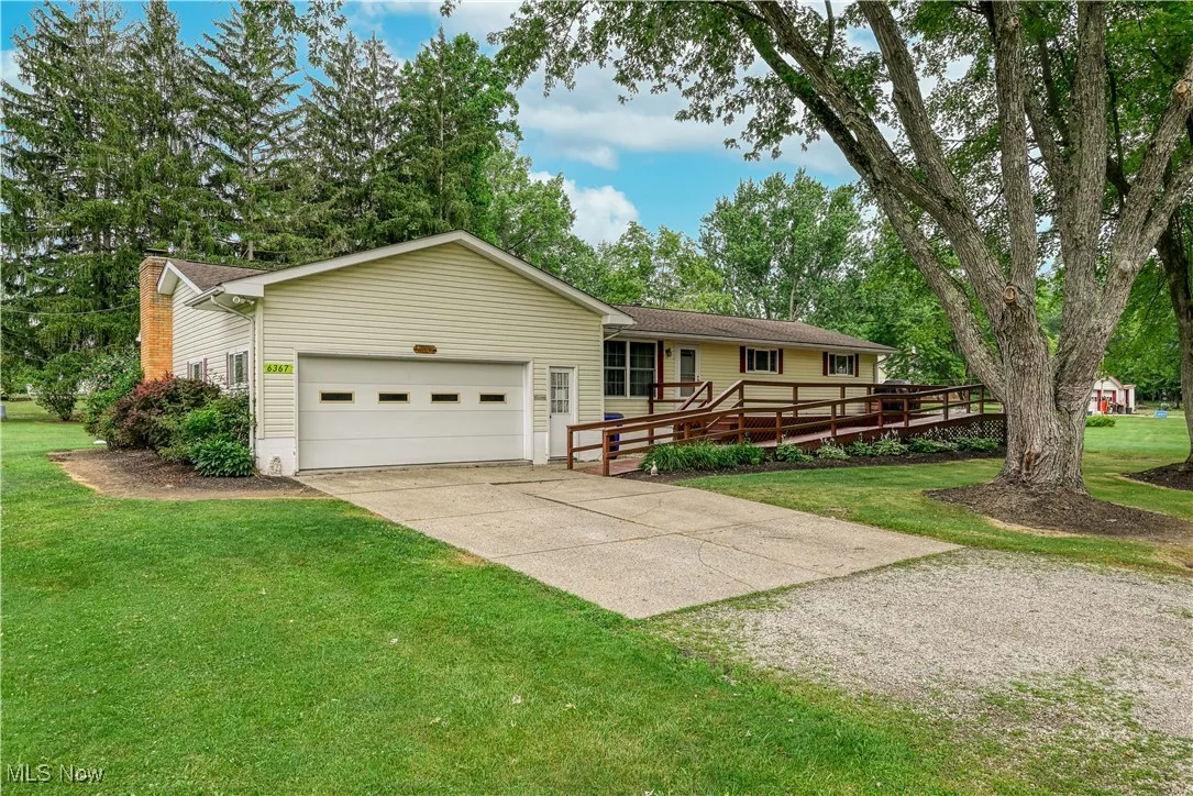 Ranch-style home with driveway, an attached garage, and a front yard