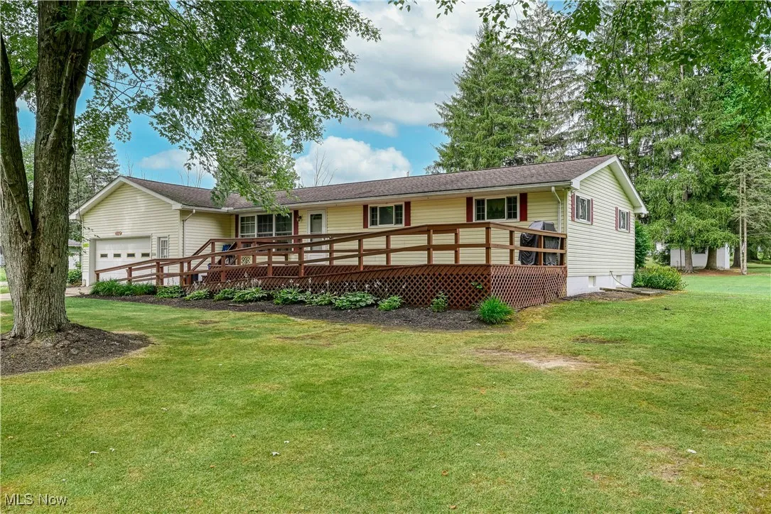 Ranch-style house featuring a garage, a front lawn, a wooden deck, and crawl space