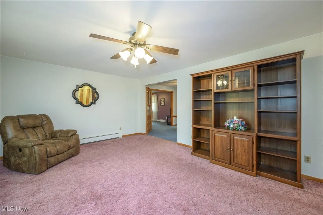 Living area featuring a baseboard radiator, a ceiling fan, and carpet flooring
