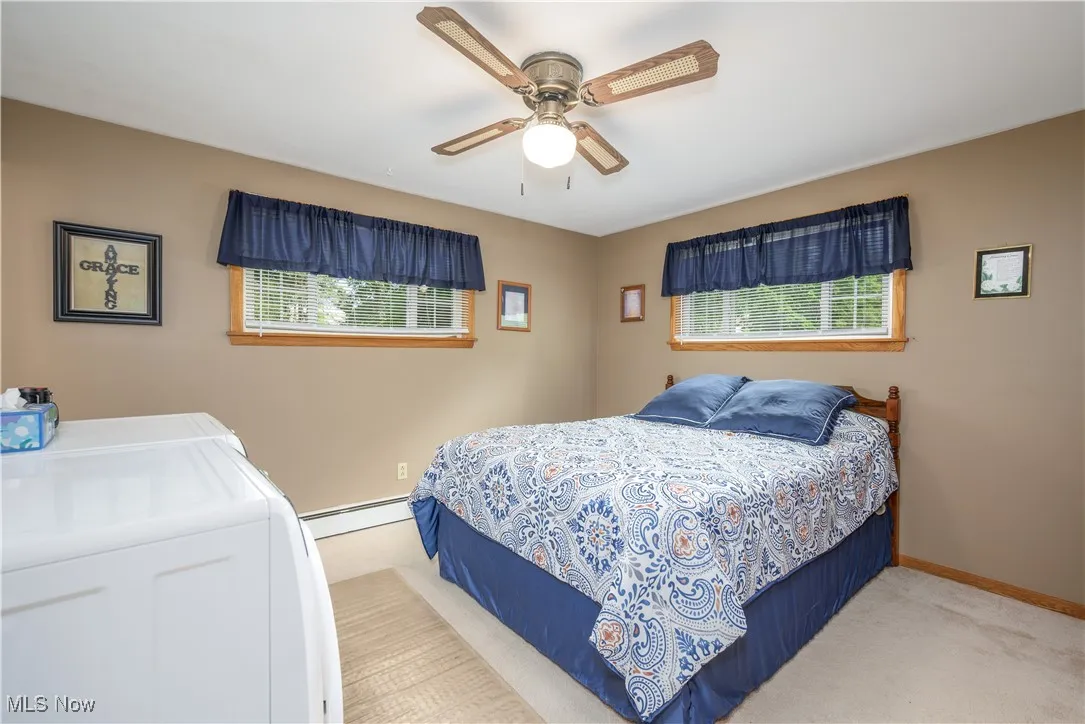 Bedroom with multiple windows, a baseboard heating unit, washing machine and clothes dryer, and carpet floors
