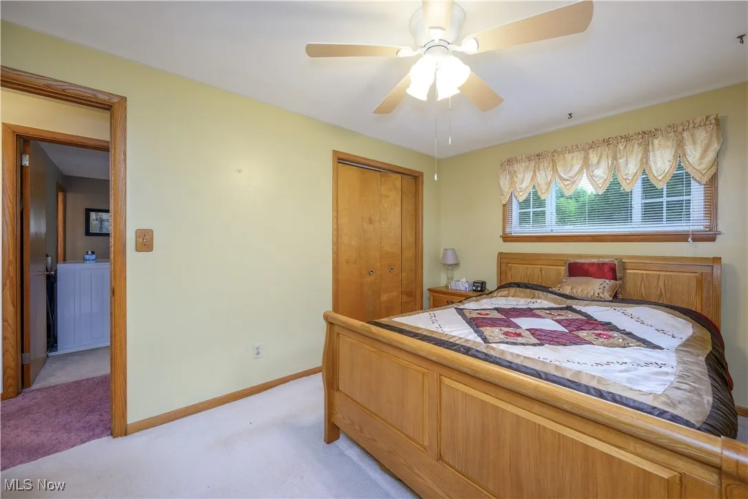 Bedroom with light carpet, a closet, and ceiling fan