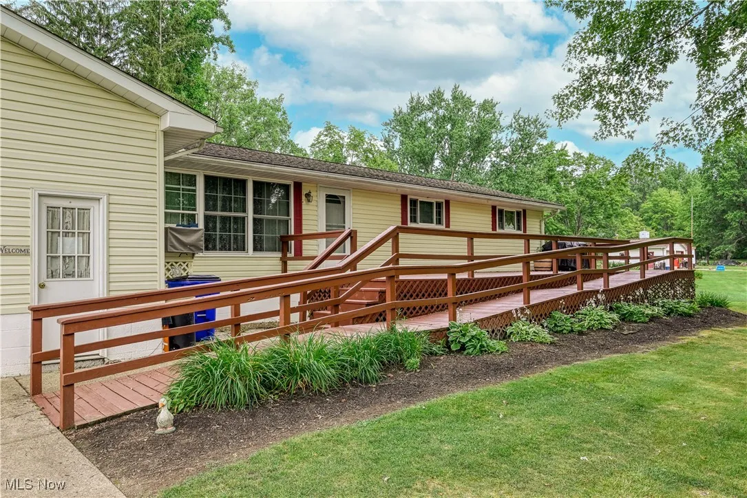 View of front facade with a wooden deck and a front lawn