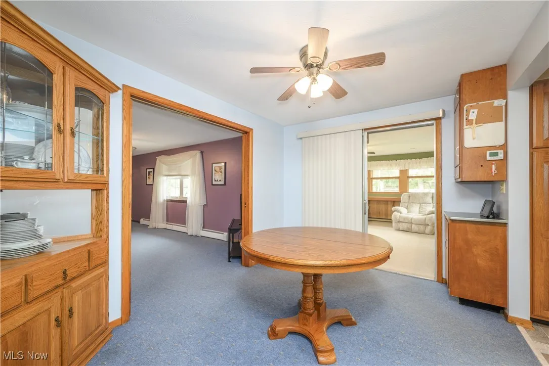 Carpeted dining area featuring ceiling fan, plenty of natural light, and baseboard heating