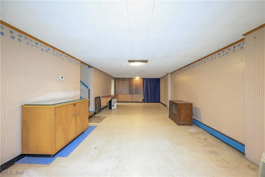 Finished basement featuring light floors, a baseboard heating unit, and concrete block wall
