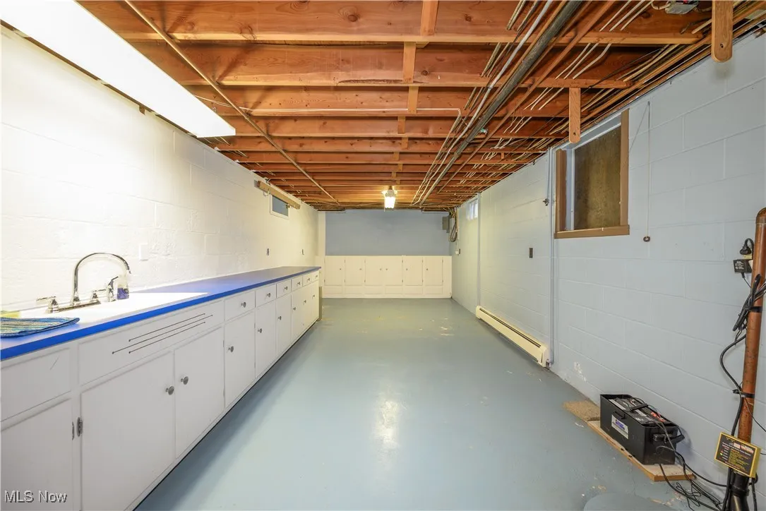 Unfinished basement featuring a baseboard radiator and concrete block wall