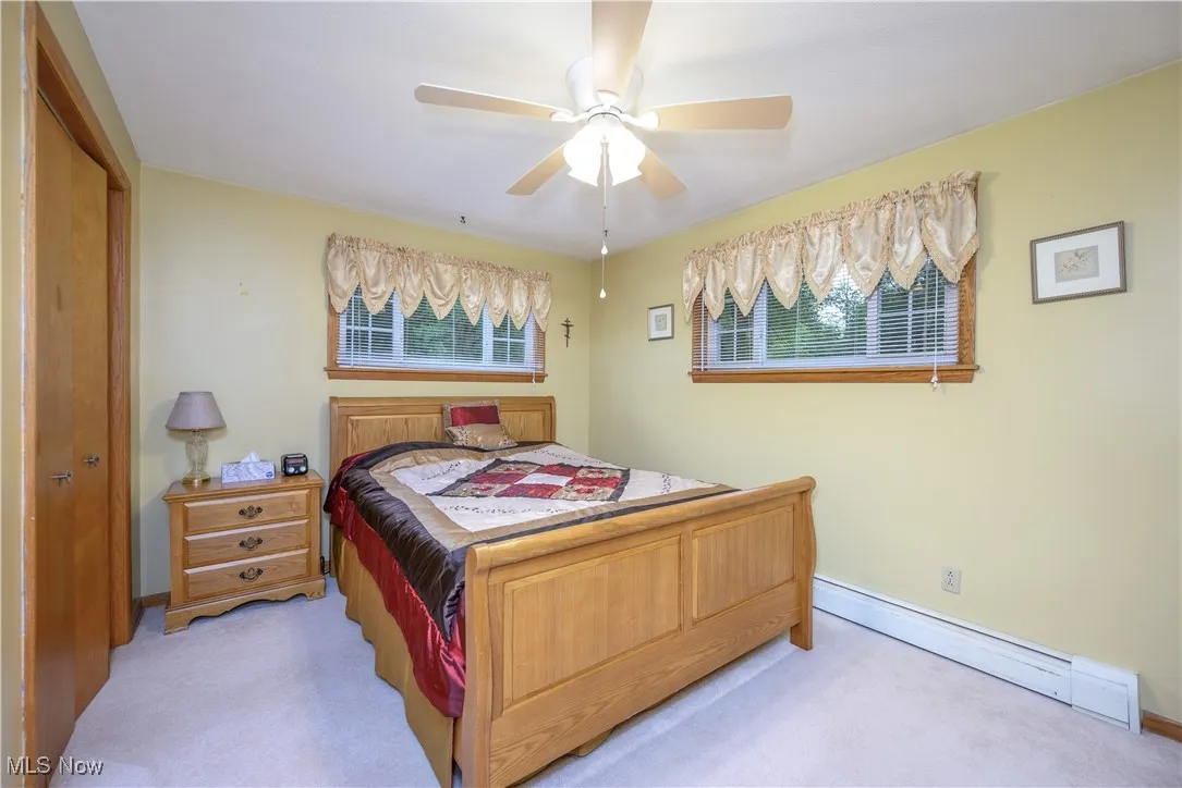 Bedroom featuring baseboard heating, light carpet, and a ceiling fan