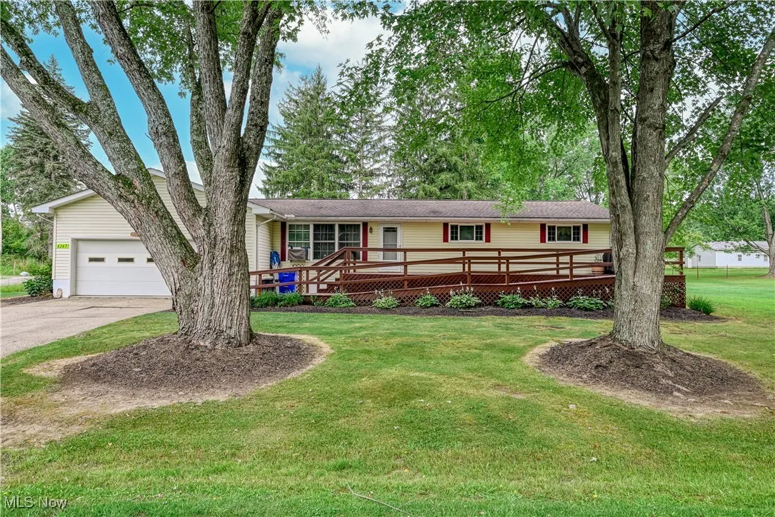 Single story home with driveway, an attached garage, a front lawn, and a deck