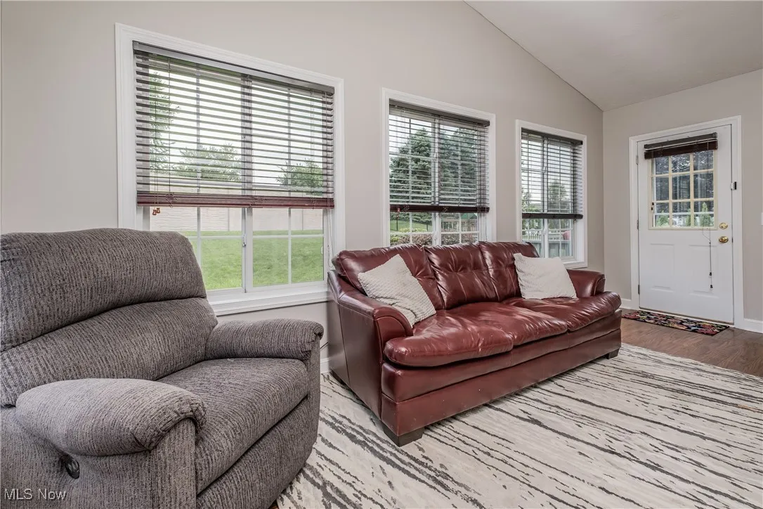 Living area with wood finished floors, plenty of natural light, and lofted ceiling