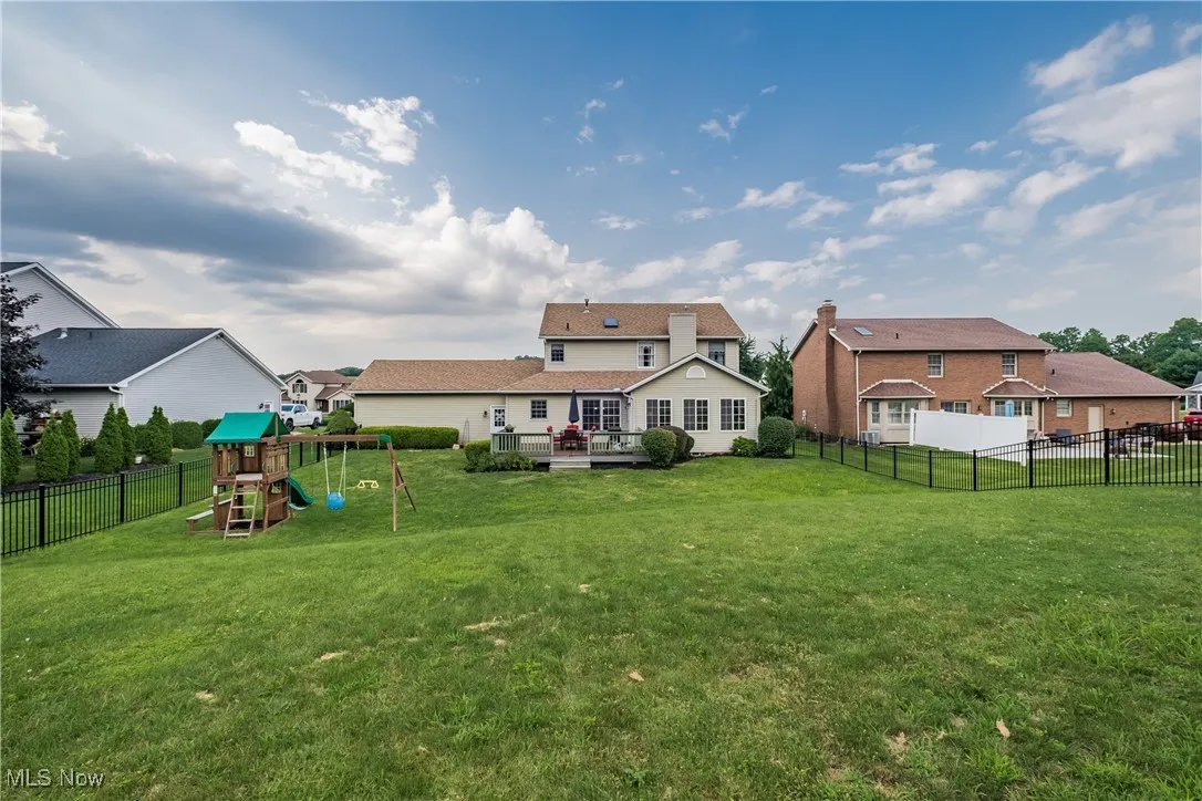 Back of property with a playground, a wooden deck, a fenced backyard, and a residential view