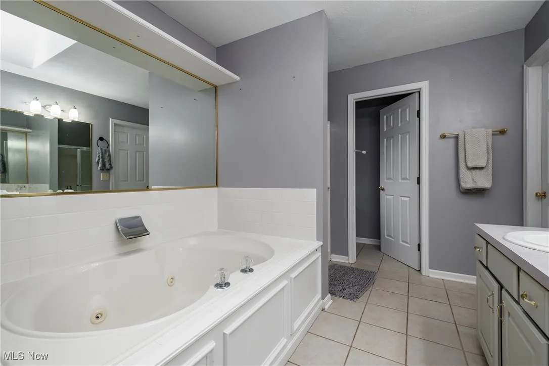Bathroom featuring vanity, a jetted tub, tile patterned floors, and a shower stall