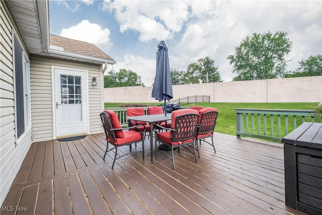 Wooden terrace with outdoor dining space and a fenced backyard