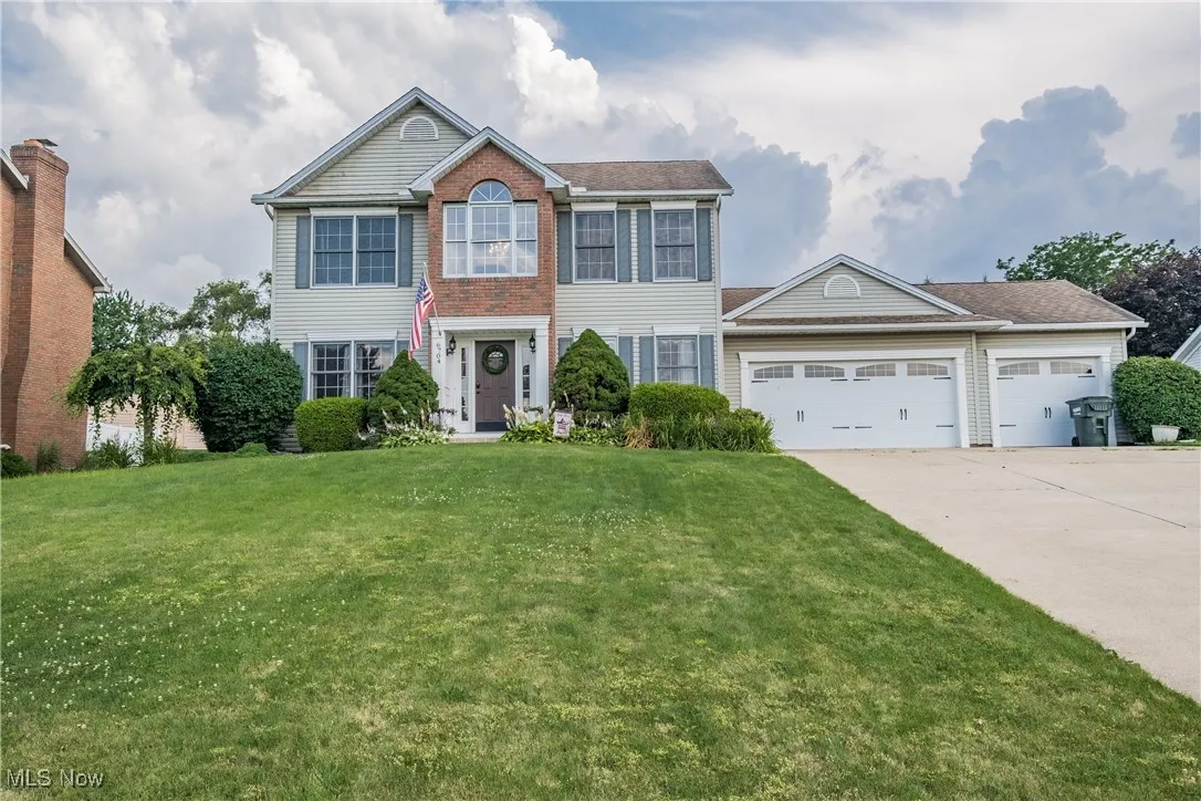 Colonial house with a garage, concrete driveway, and a front yard