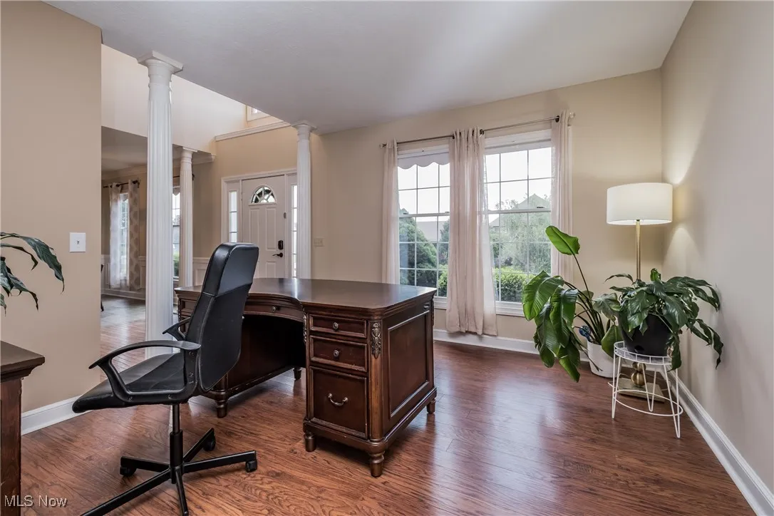 Home office featuring ornate columns and dark wood finished floors