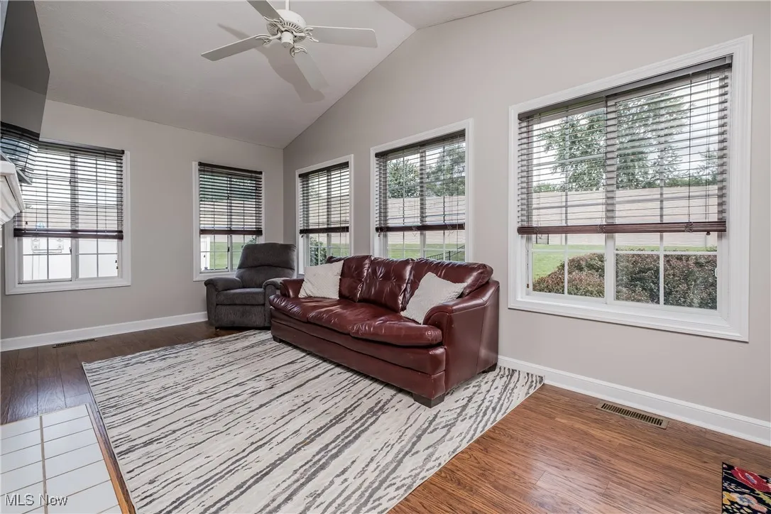 Living area with healthy amount of natural light, wood finished floors, ceiling fan, and vaulted ceiling