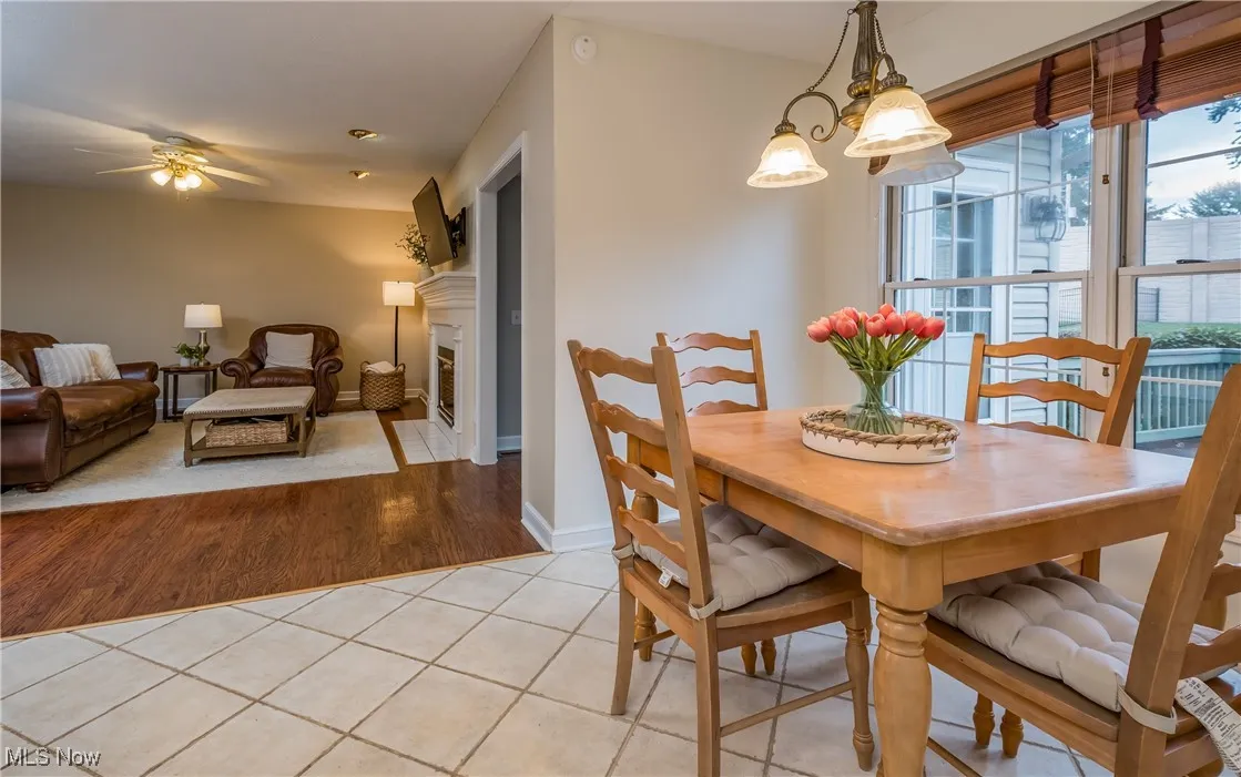 Dining room with a ceiling fan, light tile patterned floors, and a fireplace with flush hearth