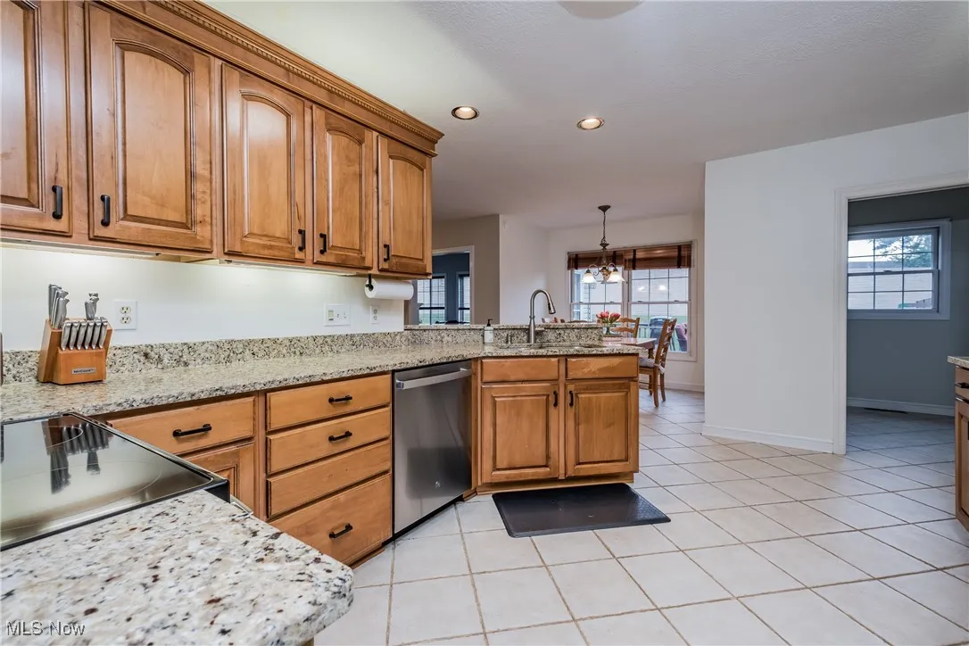 Kitchen featuring stainless steel dishwasher, brown cabinets, a peninsula, healthy amount of natural light, and recessed lighting