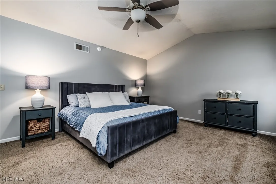 Bedroom with vaulted ceiling, carpet flooring, and ceiling fan