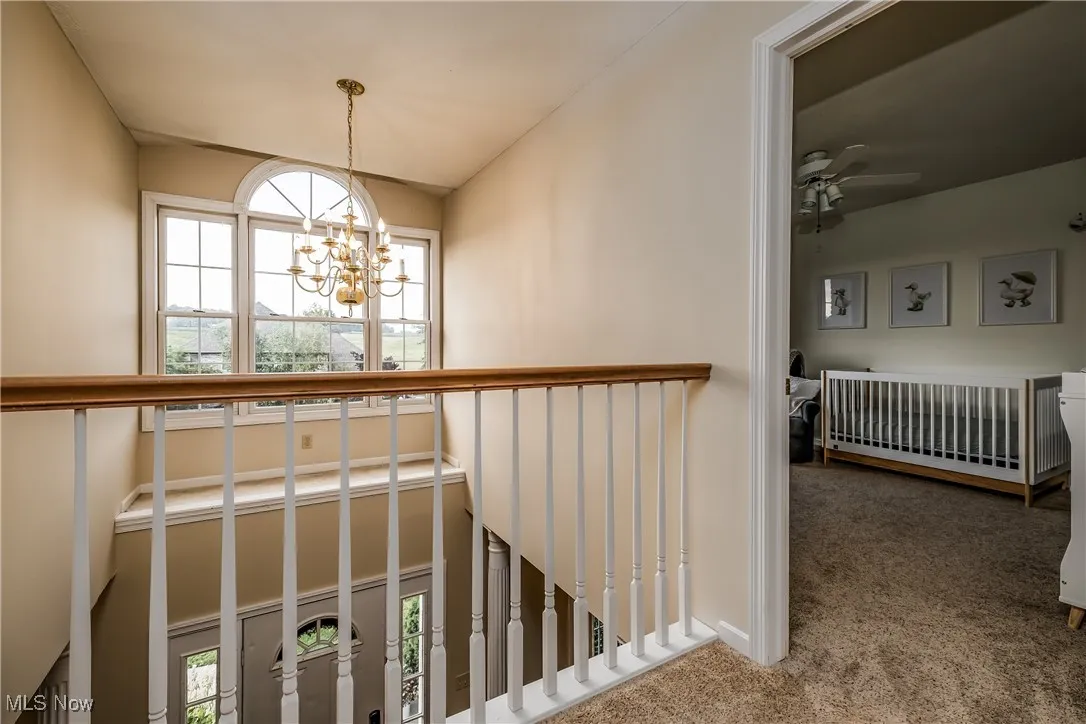 Stairs with carpet, a chandelier, lofted ceiling, and a ceiling fan