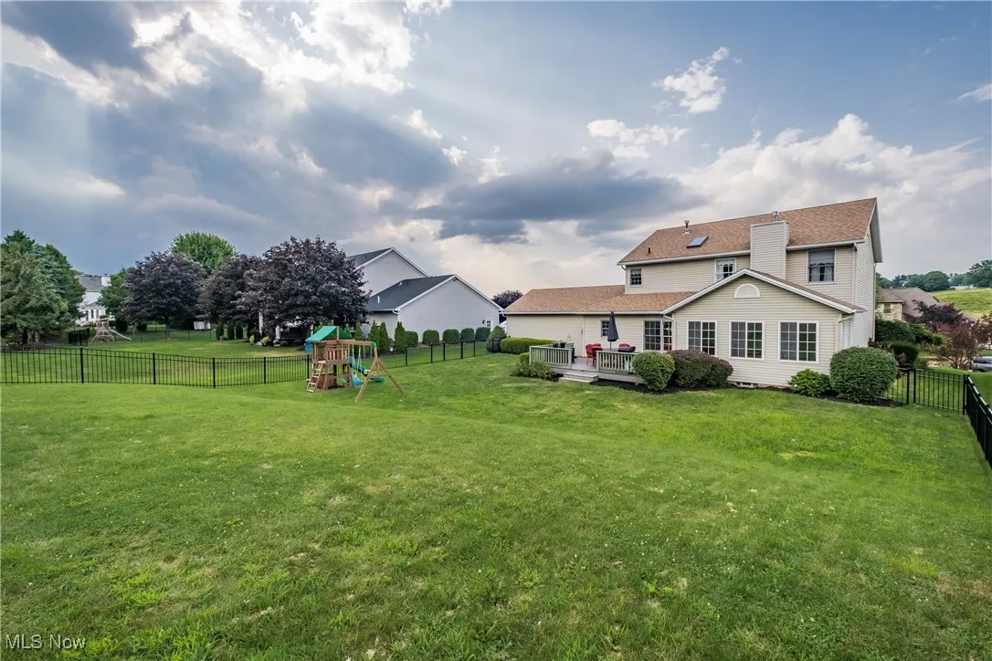 Fenced backyard with a playground and a wooden deck