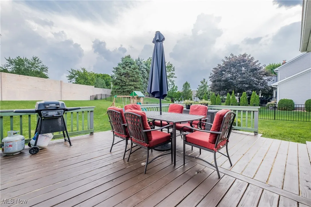 Deck with outdoor dining area, a fenced backyard, and a grill