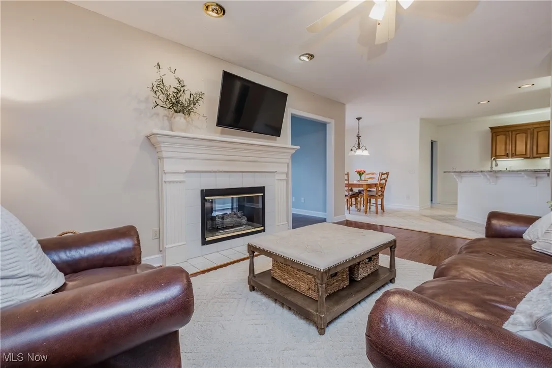 Living room featuring ceiling fan, light wood-style floors, recessed lighting, and a tiled fireplace