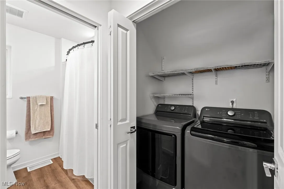 Laundry area with independent washer and dryer and wood finished floors