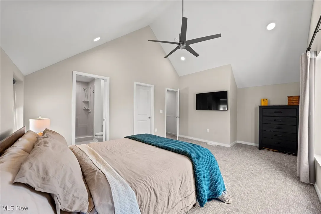 Carpeted bedroom with recessed lighting, a ceiling fan, ensuite bathroom, and high vaulted ceiling