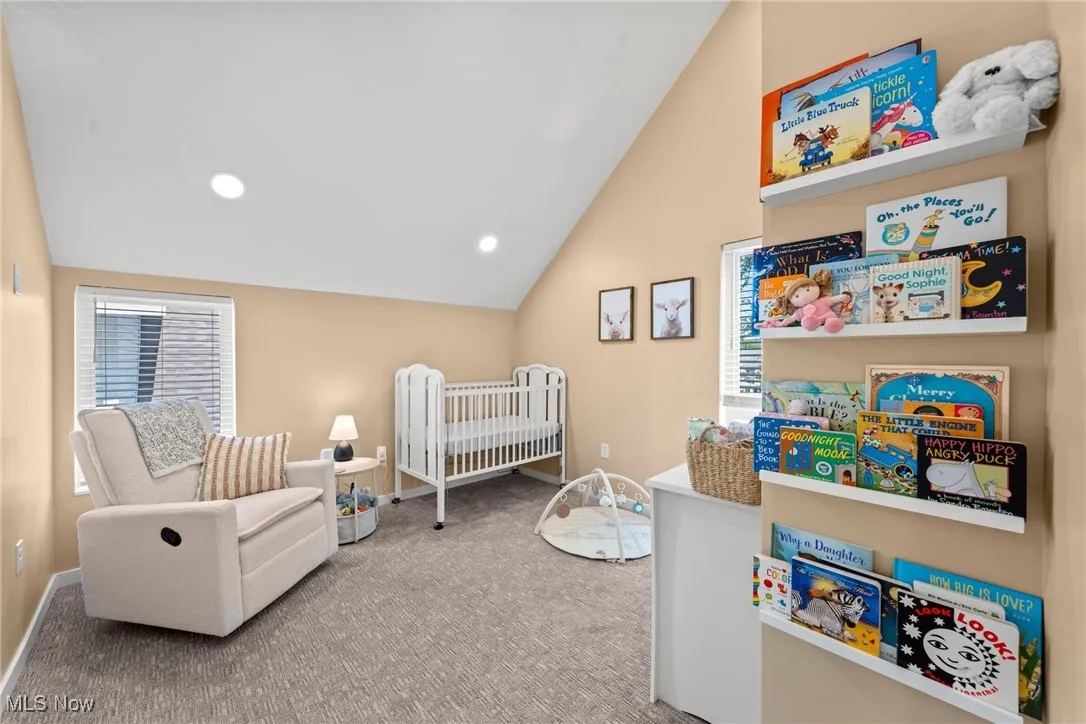 Carpeted bedroom featuring vaulted ceiling and a crib
