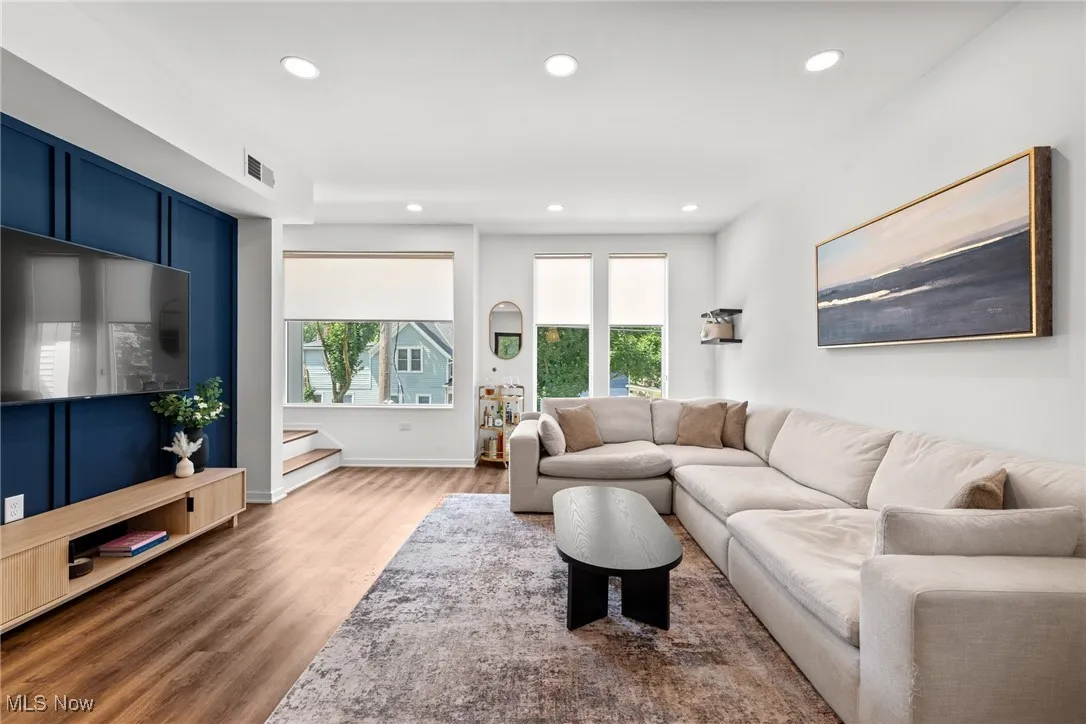 Living area with plenty of natural light, wood finished floors, recessed lighting, and stairs