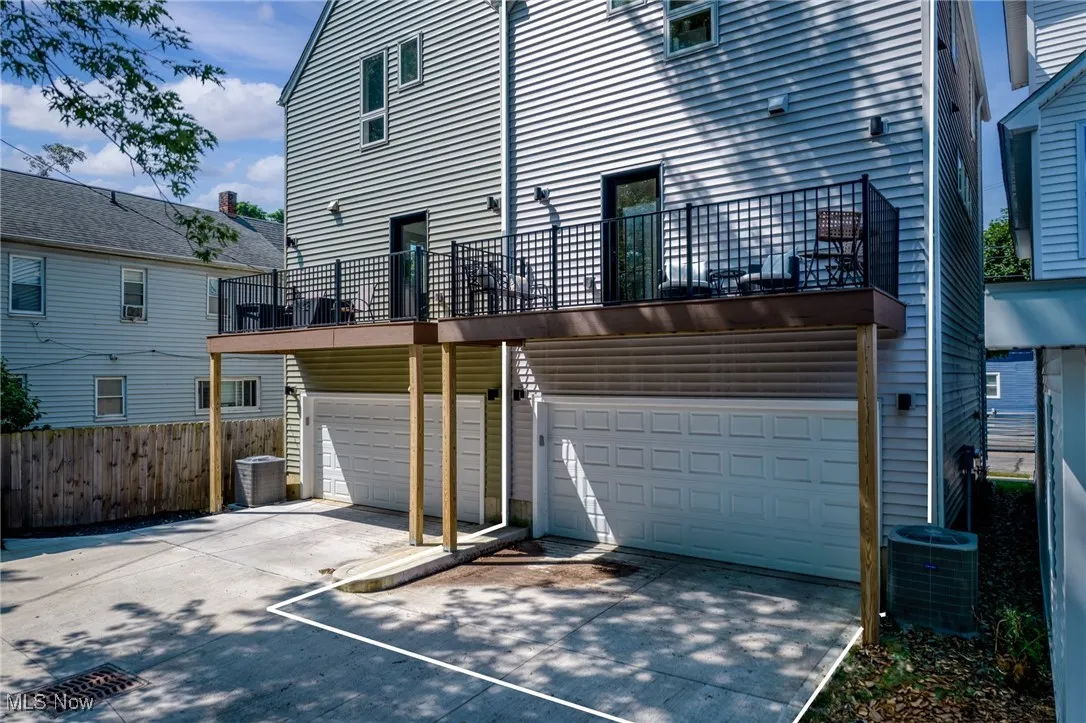Back of house featuring an attached garage, a balcony, and driveway