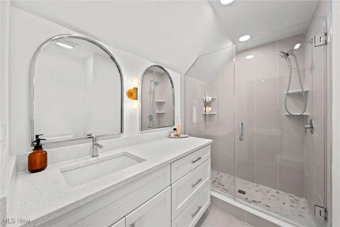 Full bath with a shower stall, vanity, recessed lighting, vaulted ceiling, and tile patterned floors
