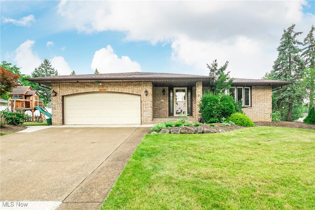 View of front of home with brick siding, concrete driveway, a garage, and a front yard