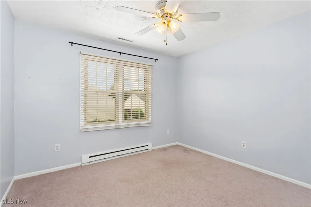 Unfurnished room featuring a baseboard radiator, carpet floors, ceiling fan, and a textured ceiling