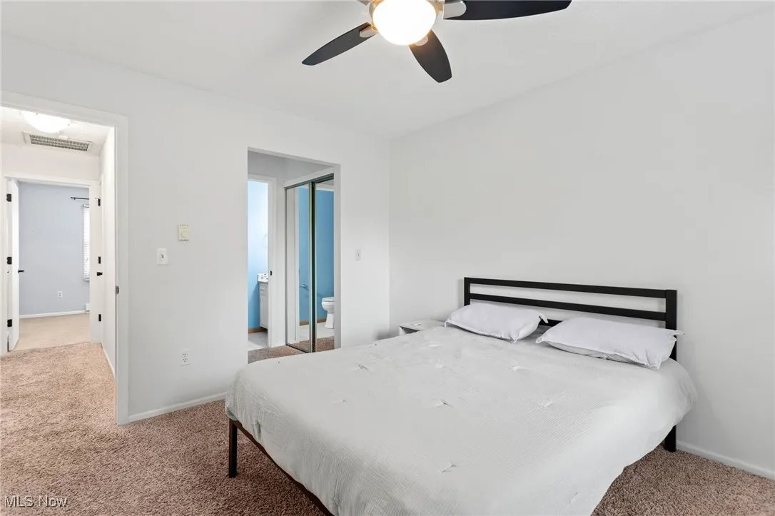 Carpeted bedroom with ceiling fan and ensuite bathroom