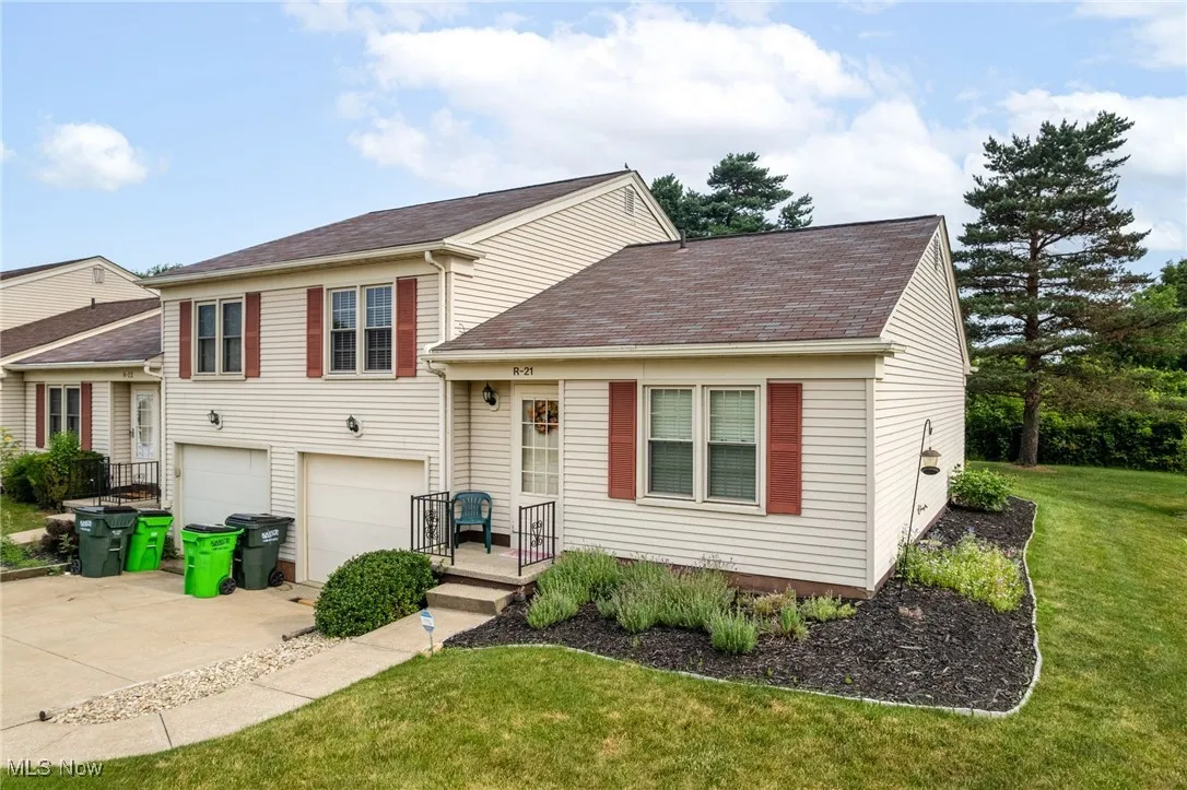 Tri-level home with driveway, an attached garage, roof with shingles, and a front yard