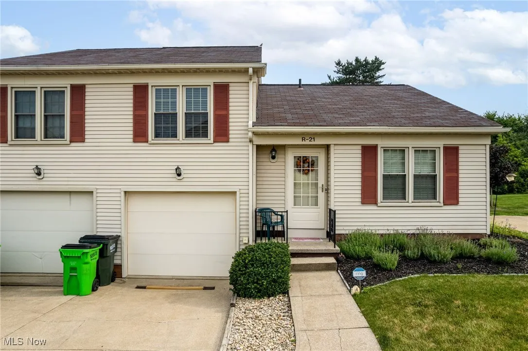Tri-level home with an attached garage, driveway, a shingled roof, and a front lawn