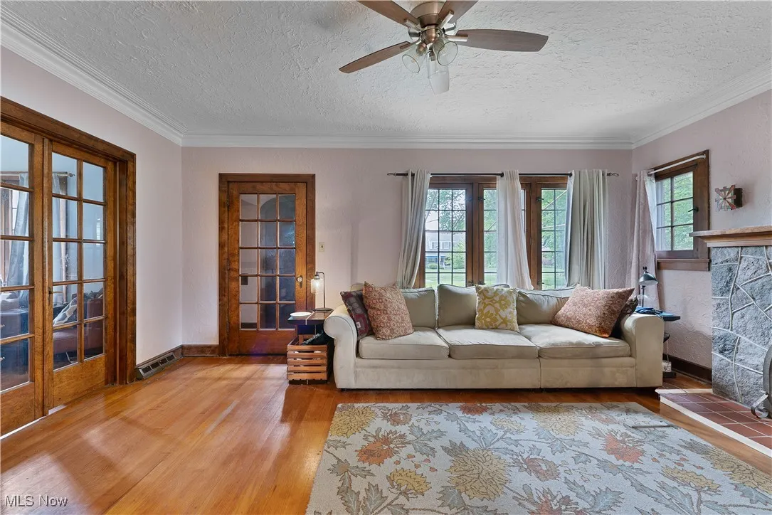 Living room featuring light wood-style flooring, ornamental molding, ceiling fan, and a textured ceiling