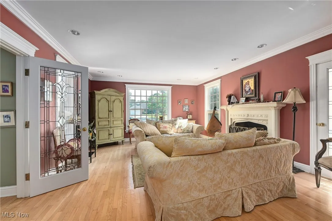 Living room featuring light wood-type flooring, a fireplace, ornamental molding, and recessed lighting