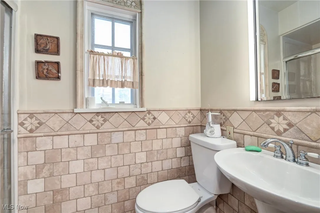 Bathroom with tile walls, a wainscoted wall, healthy amount of natural light, and a shower stall