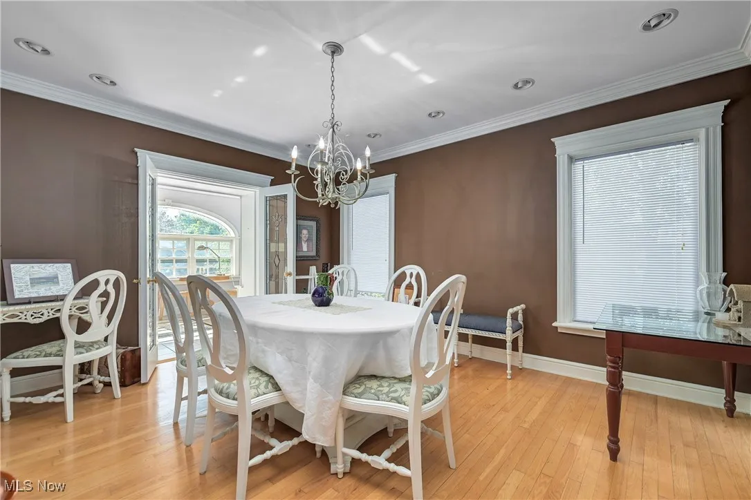 Dining area with a chandelier, crown molding, light wood-style flooring, and recessed lighting
